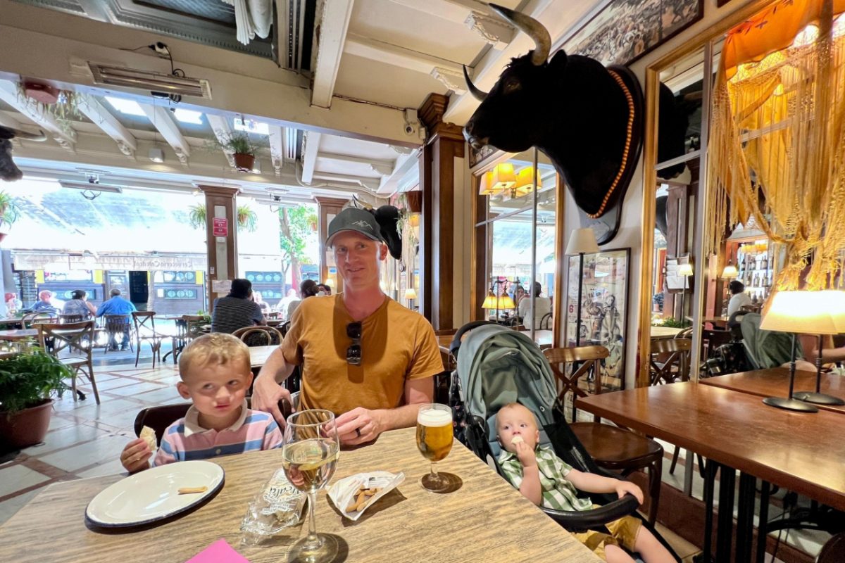 Family mealtime in a traditional Spanish restaurant with a father, toddler, and baby, exemplifying how you can easily travel with a toddler in Spain