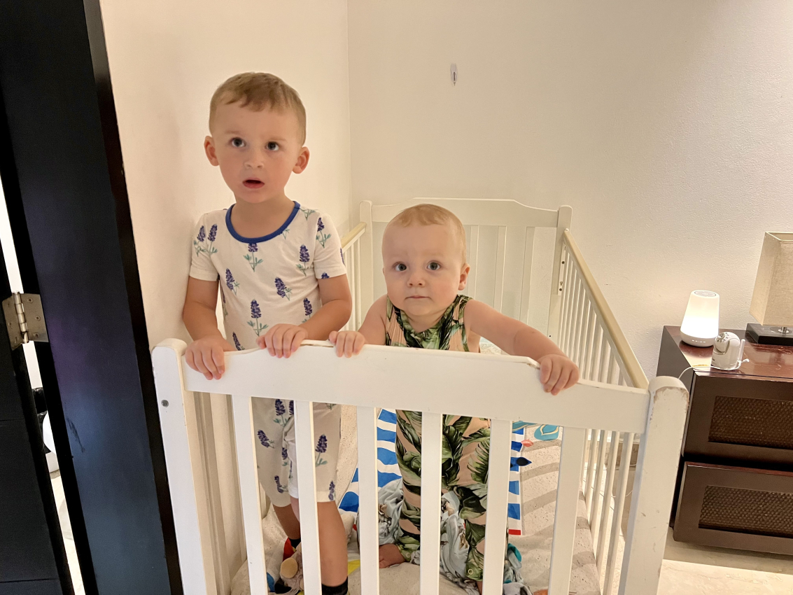 Kids in their bedtime attire in a crib, a common end to a day filled with adventure in Mexico with toddlers.