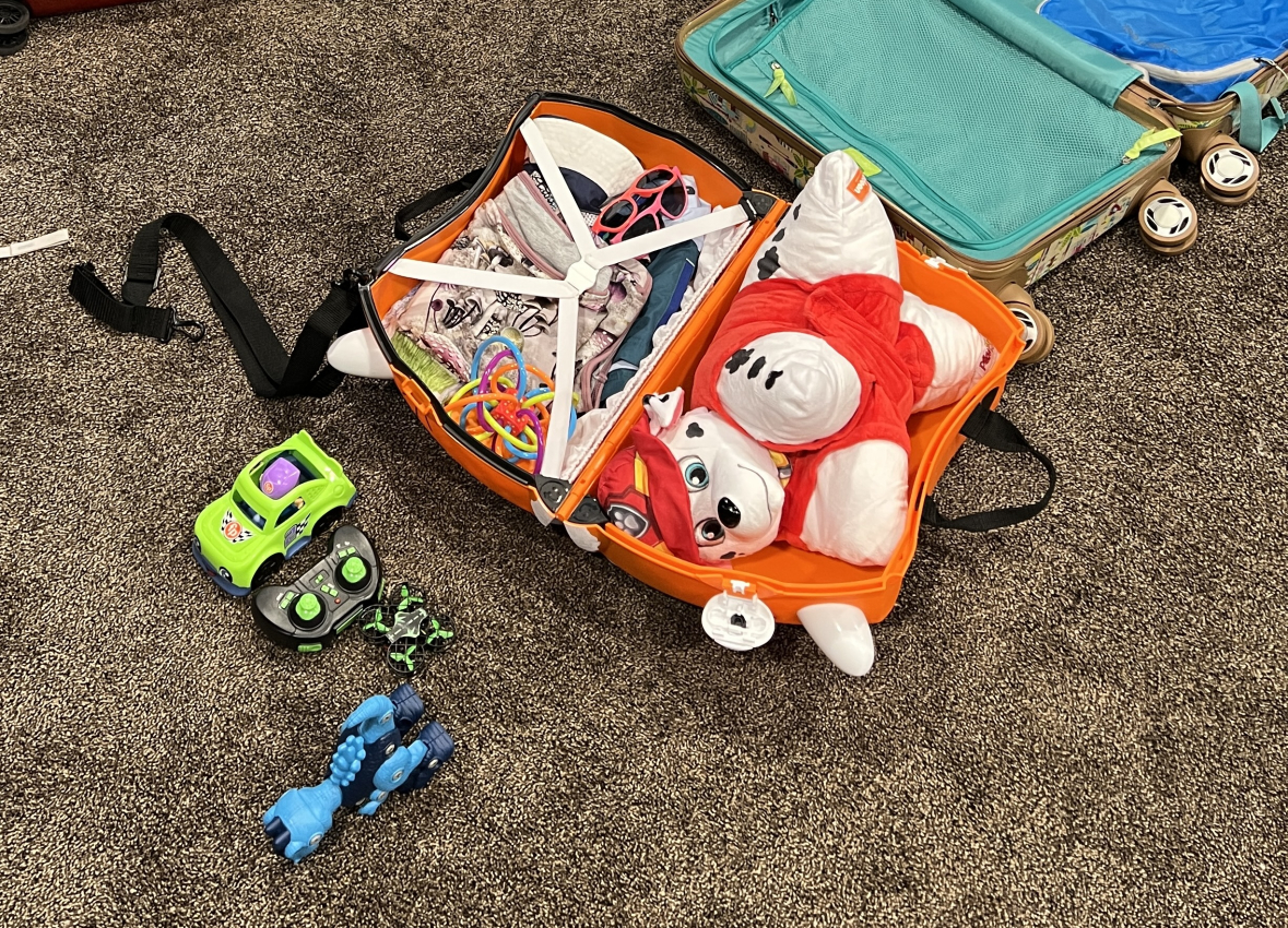 Open ride-on suitcase filled with toys and clothes, revealing how it keeps children's essentials and entertainment in one place.