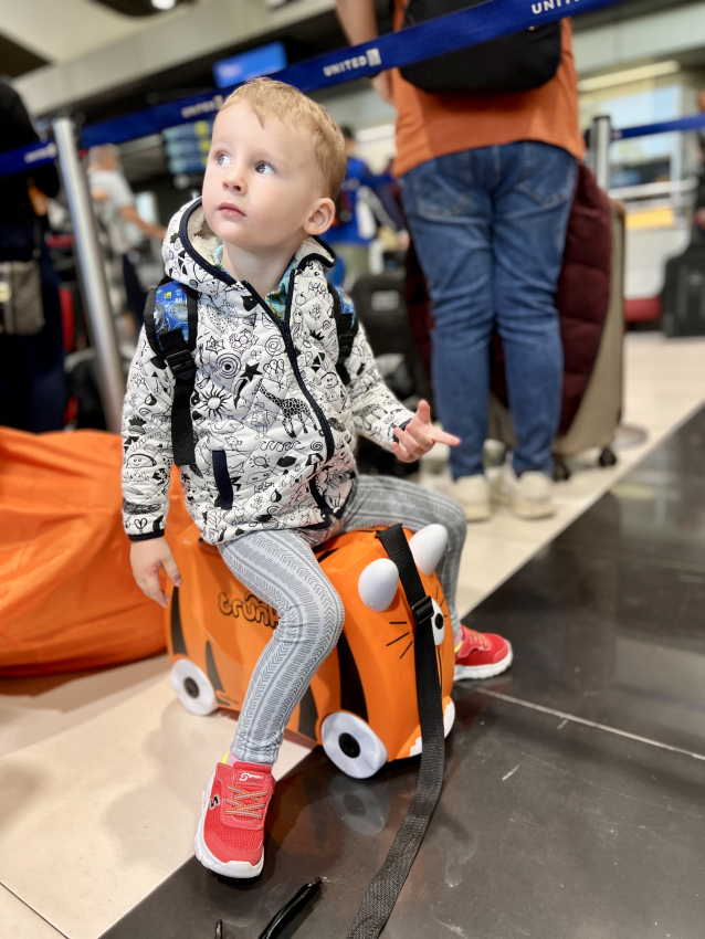 Toddler riding trunki ride on suitcase at the airport