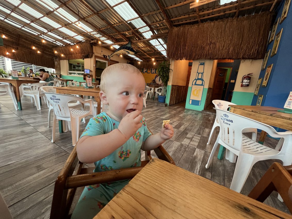 Baby trying out snacks at a quaint café, experiencing the local cuisine in Mexico with family.
