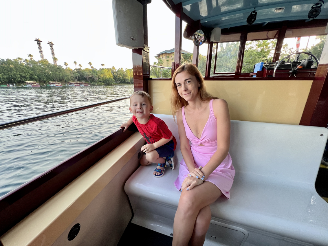 Mother and son enjoying a boat ride with a scenic view of palm trees and waterways, perfect for those with a Universal Express Pass looking to relax after skipping the lines at Universal Studios.