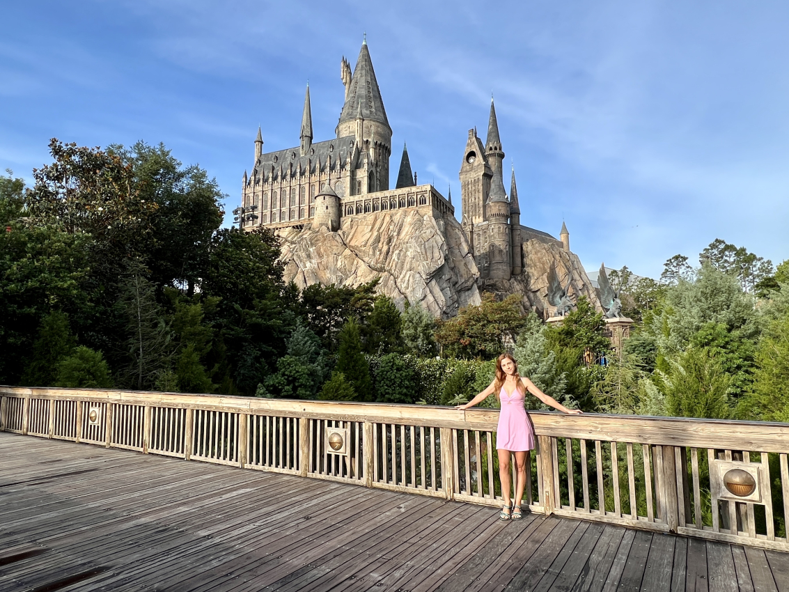 Women in pink dress standing in front of the Hogwarts Castle at Universal Studios with no lines.