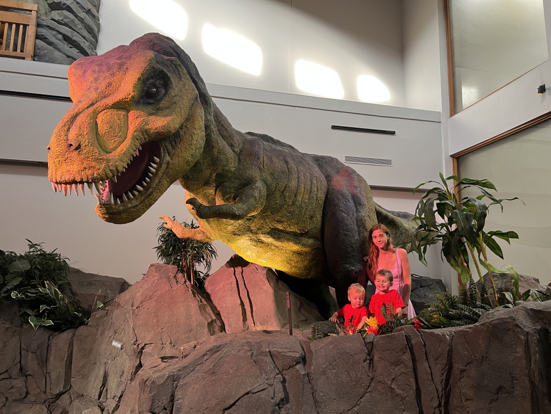 Family posing with a giant T-Rex, a thrilling encounter at Universal Studios Orlando's dinosaur attraction for toddlers.
