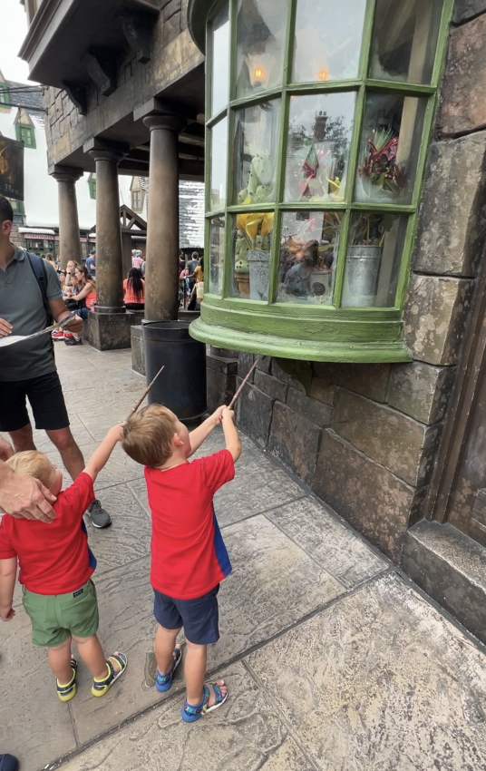 Toddlers pointing wands at an enchanted window, a magical moment captured at Universal Studios Orlando with toddlers.
