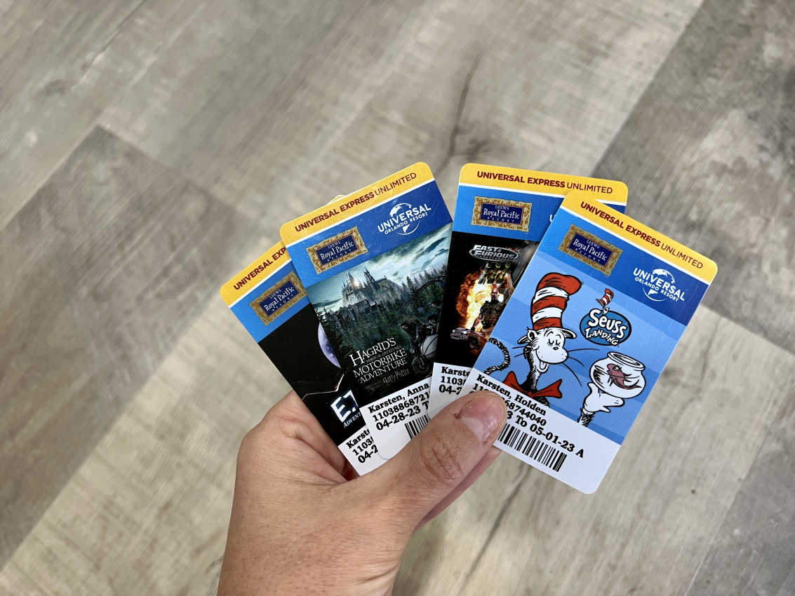 Hand holding a collection of Universal Express Unlimited passes featuring attractions, a savvy trick for hotel guests to maximize their time at Universal Studios.
