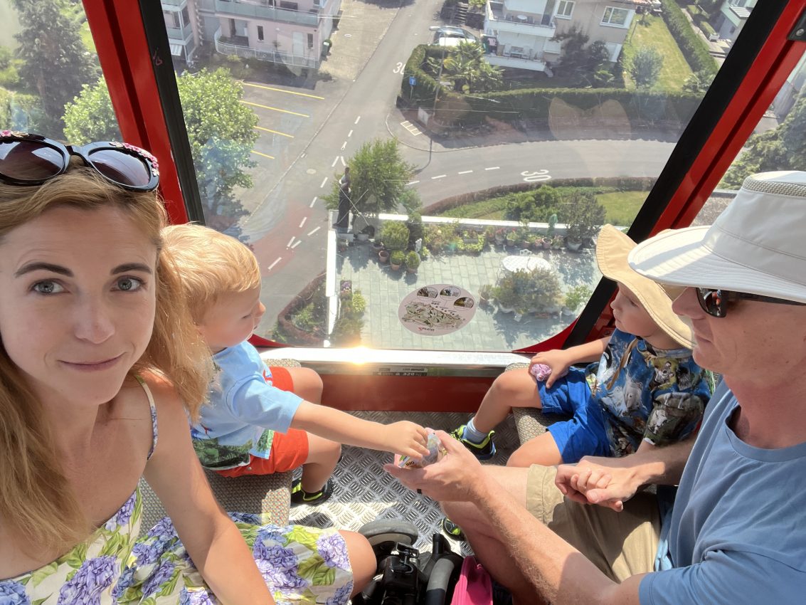 Family enjoying a panoramic cable car ride, a must-do when visiting Switzerland with kids, offering breathtaking views of the streets below.