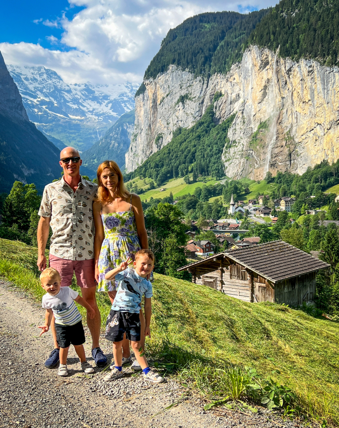 Family posing against the backdrop of a lush green valley in Switzerland, creating memories with kids on a scenic hike.
