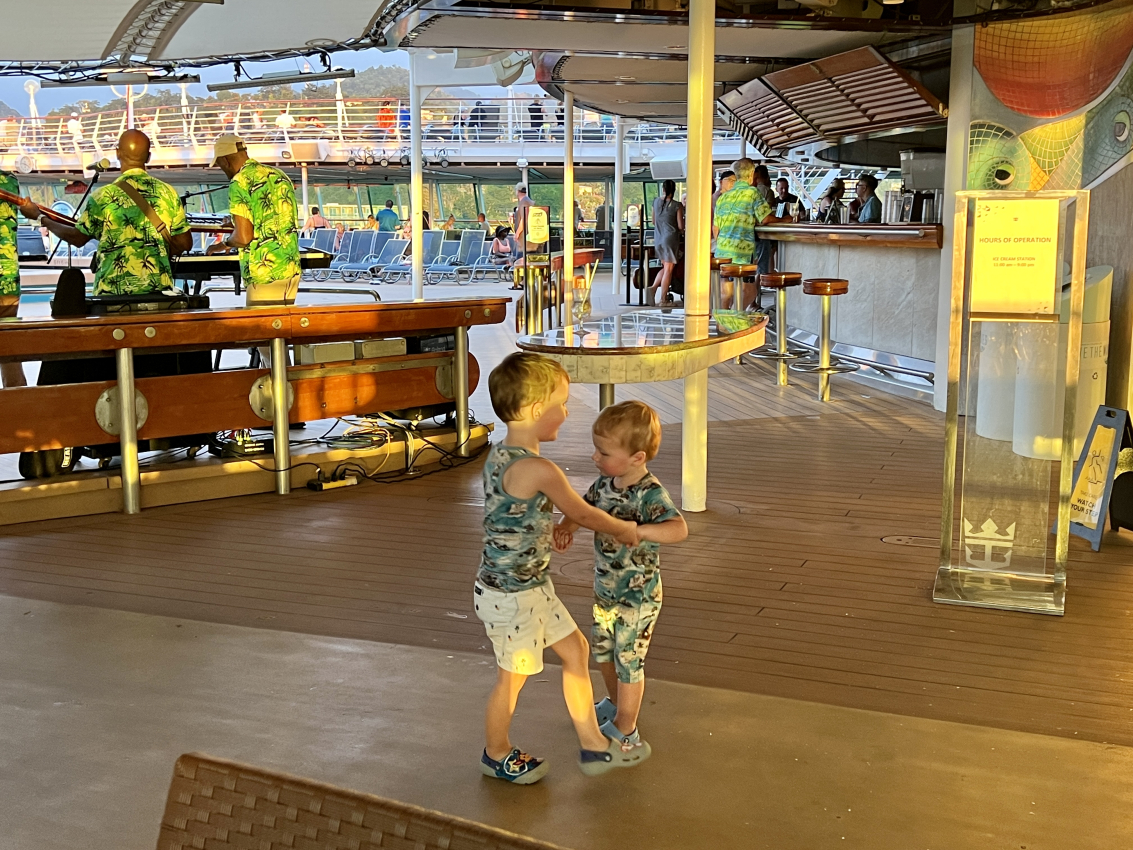 Two toddlers dancing on the deck of a cruise ship with live music, enjoying family fun while cruising with a toddler.
