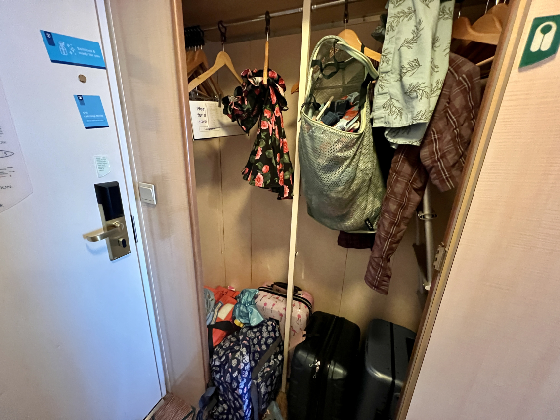 Open cruise ship wardrobe with an array of clothes and accessories, depicting the practical side of taking kids on a cruise.
