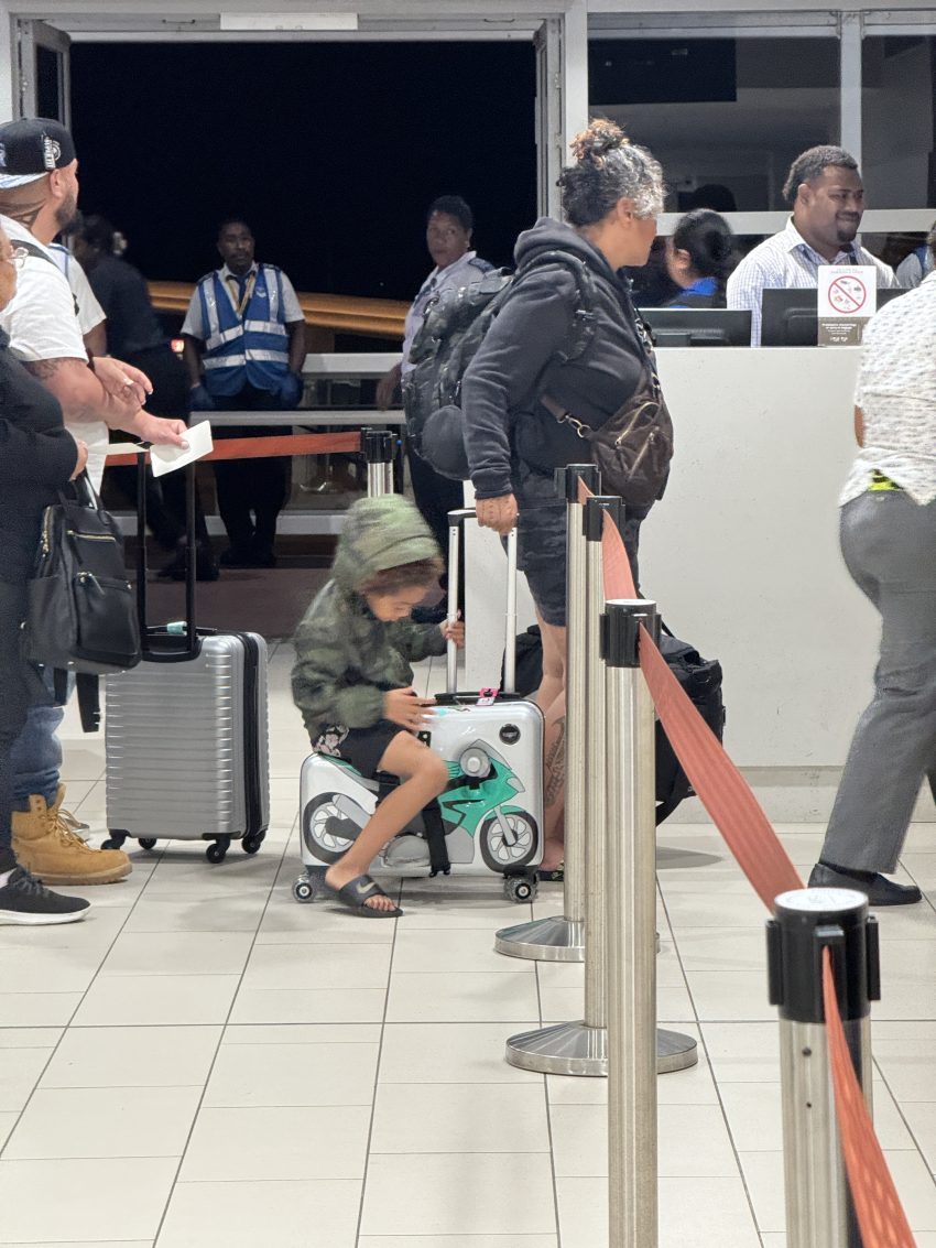 child sitting on a ride on suitcase at the airport